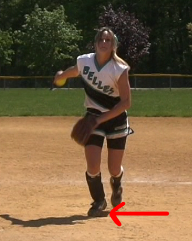 Windmill pitcher in load position with arrow indicating placement of training aid